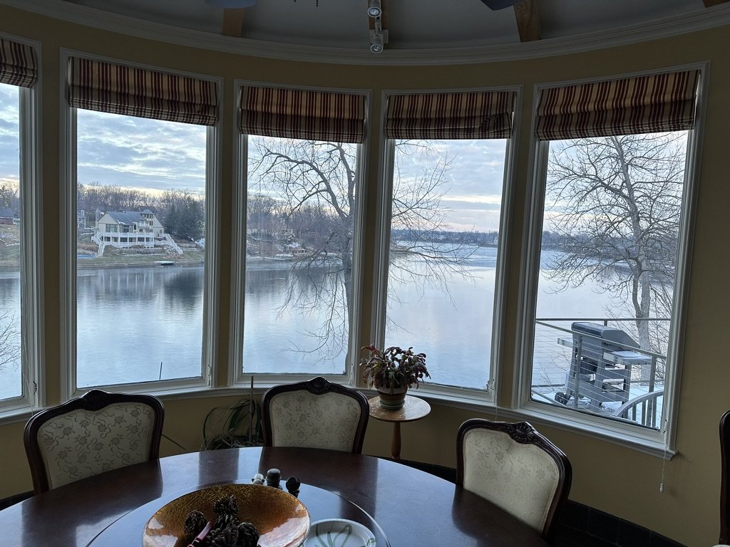 Geist Lake on a winter day, seen through a curved bay of windows above a round dining table