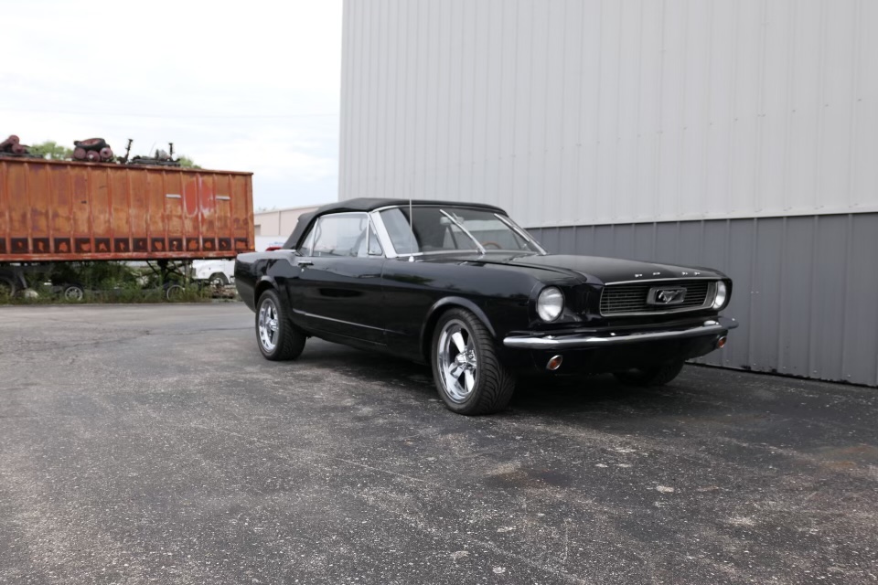 The completed black 1966 Mustang convertible parked outside with its black top raised