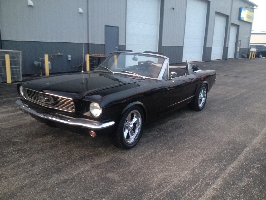 The completed black 1966 Mustang convertible parked outside with the top down