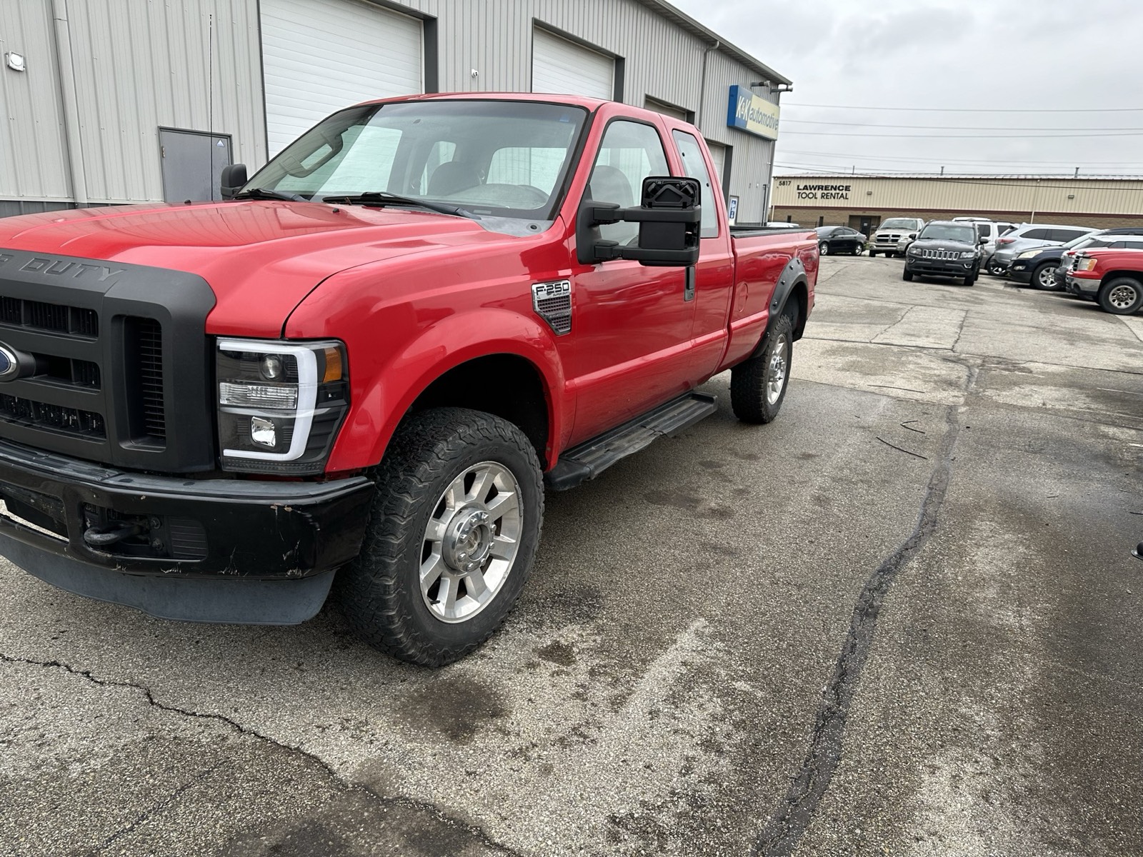 A red Ford F-250 project truck parked outside Eric's shop and K&K Automotive