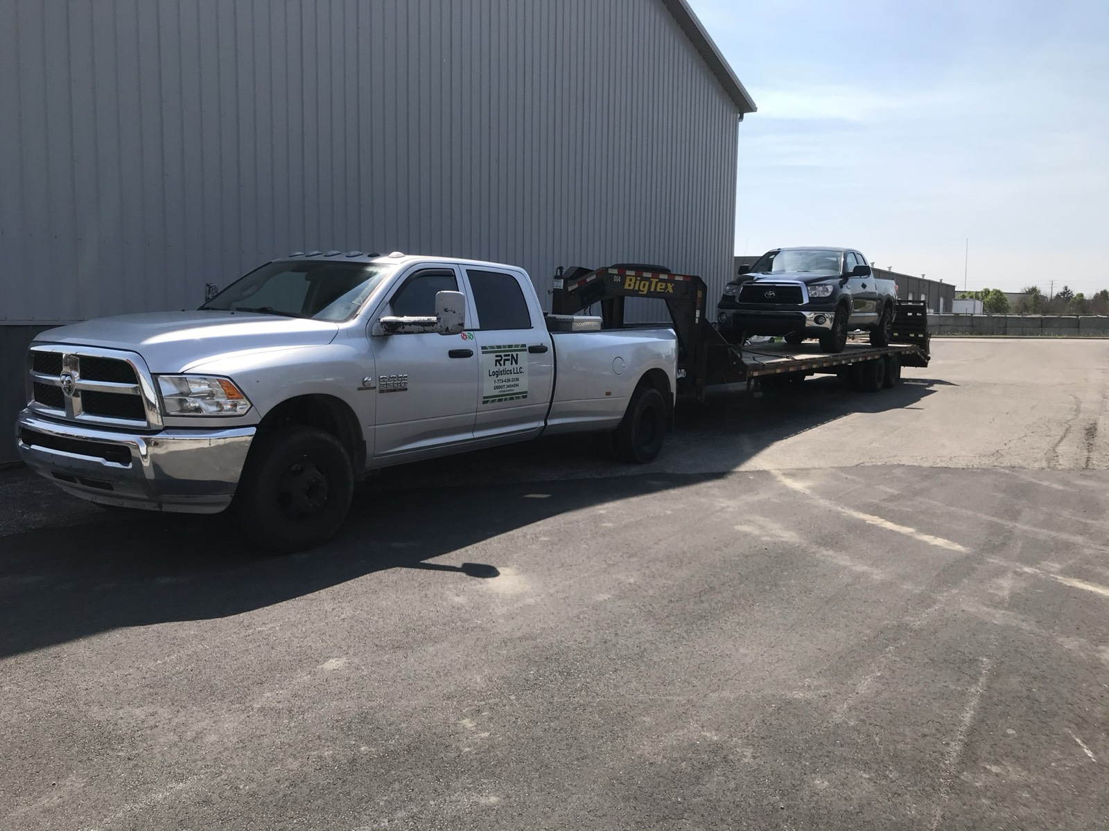 A Ram hotshot truck and 40-foot trailer carrying Eric's Toyota Tundra outside the shop